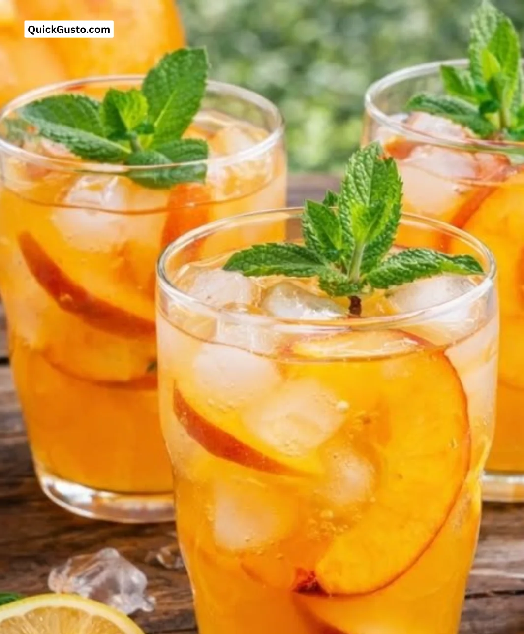 Glass of Sweet Tart Peach Lemonade with fresh peaches and lemons on a sunny table