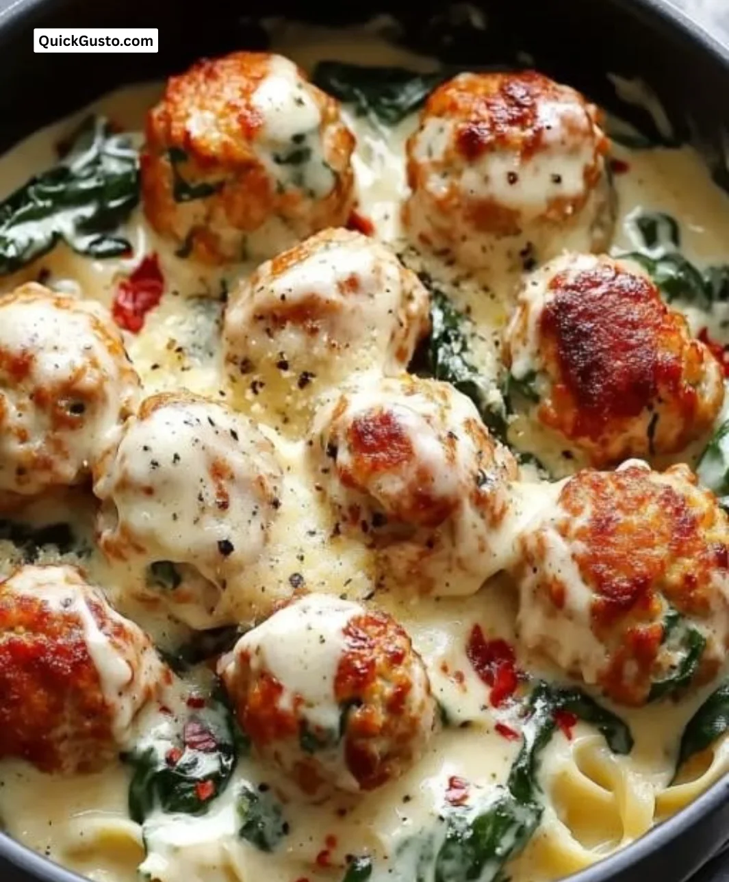 Baked chicken ricotta meatballs served with spinach Alfredo sauce in a cozy dish.