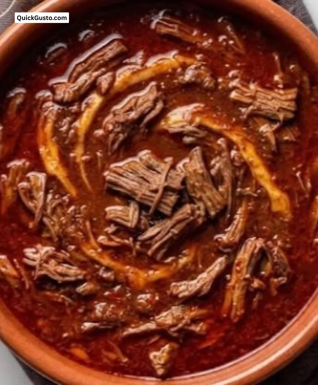 A plate of birria, showcasing tender meat and flavorful broth garnished with onions and cilantro.