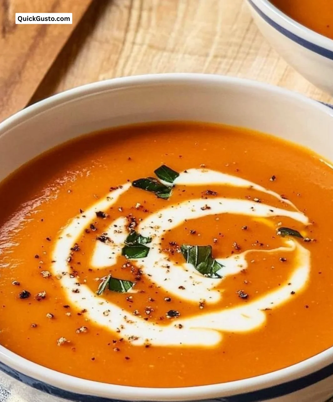 Creamy roasted tomato and red pepper soup in a rustic bowl with fresh herbs.