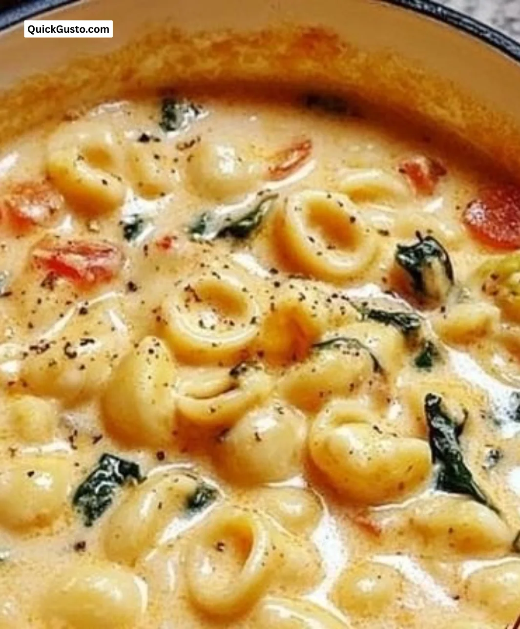 Creamy tortellini soup in a bowl with herbs and cheese garnish