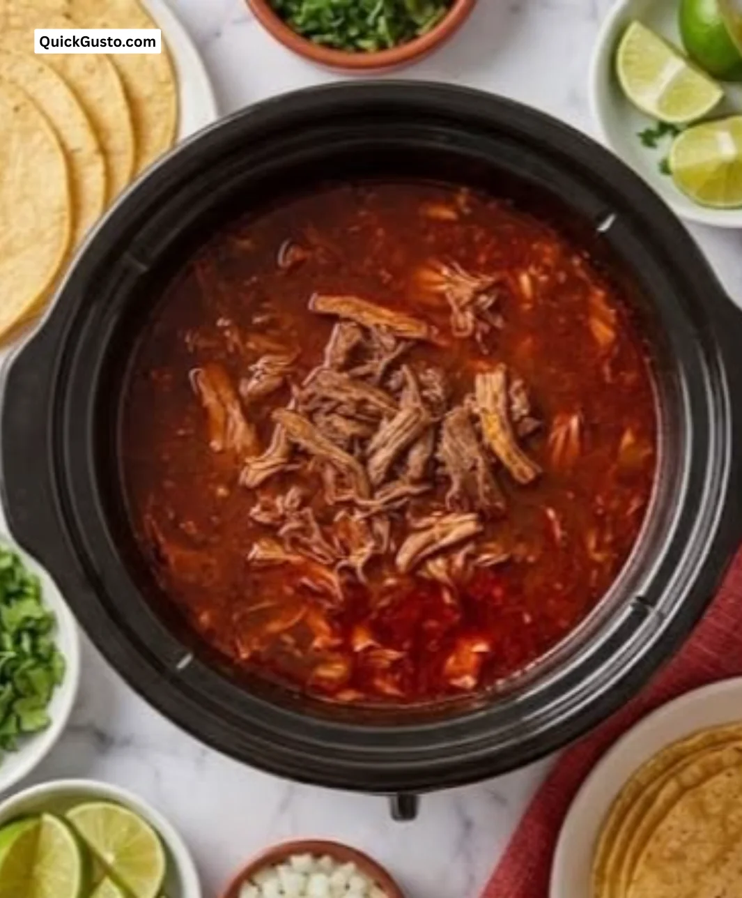 A delicious bowl of Crockpot Birria served with fresh toppings and herbs