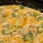 Crockpot creamy broccoli cheddar chicken served in a bowl with fresh broccoli