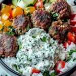 Delicious Greek Meatball Bowl topped with fresh Tzatziki sauce and vibrant vegetables.