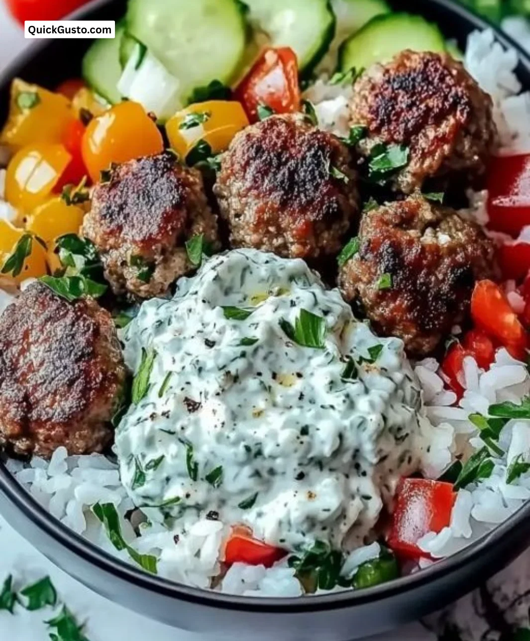 Delicious Greek Meatball Bowl topped with fresh Tzatziki sauce and vibrant vegetables.