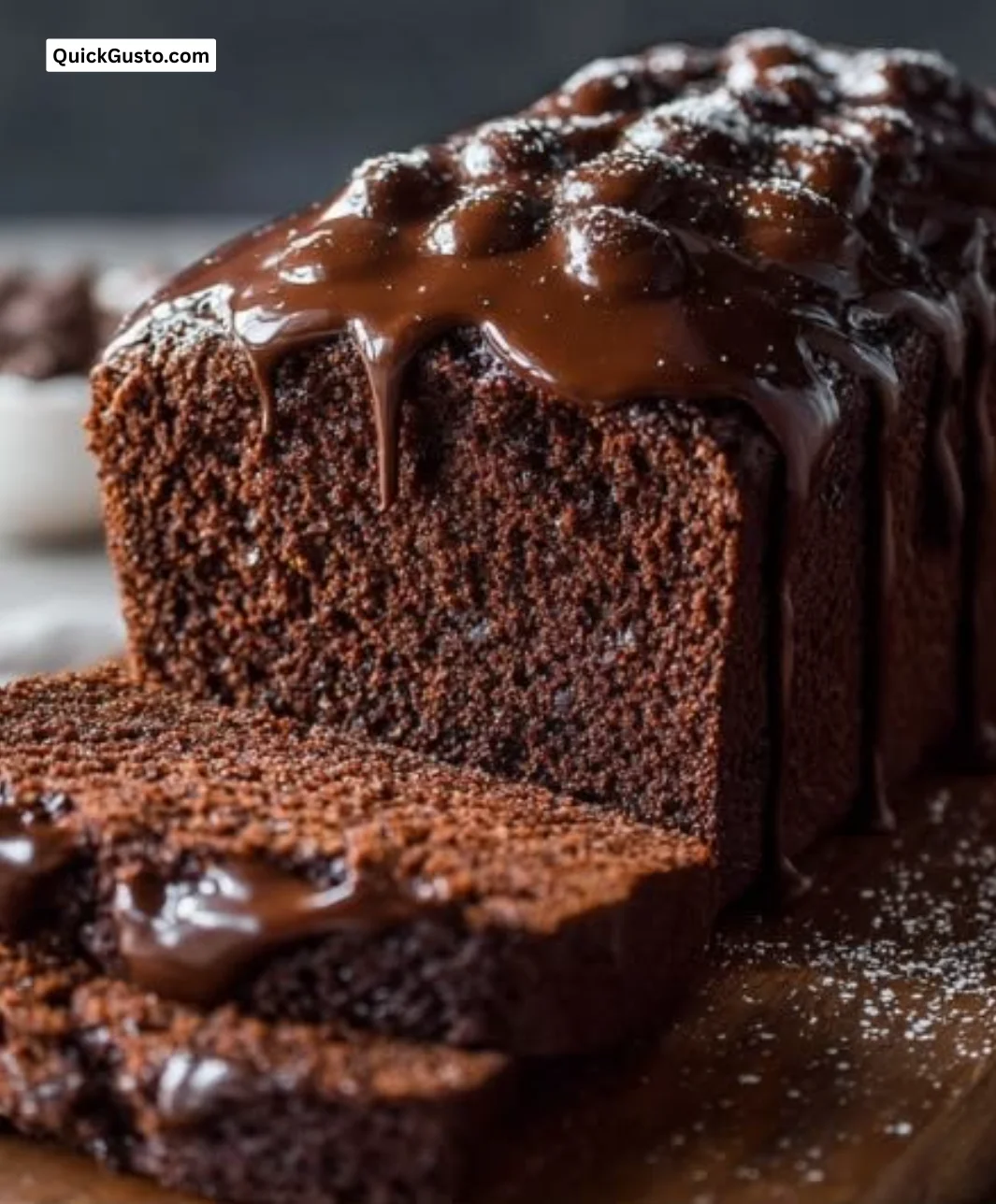 Homemade chocolate pound cake on a rustic wooden table, topped with ganache.
