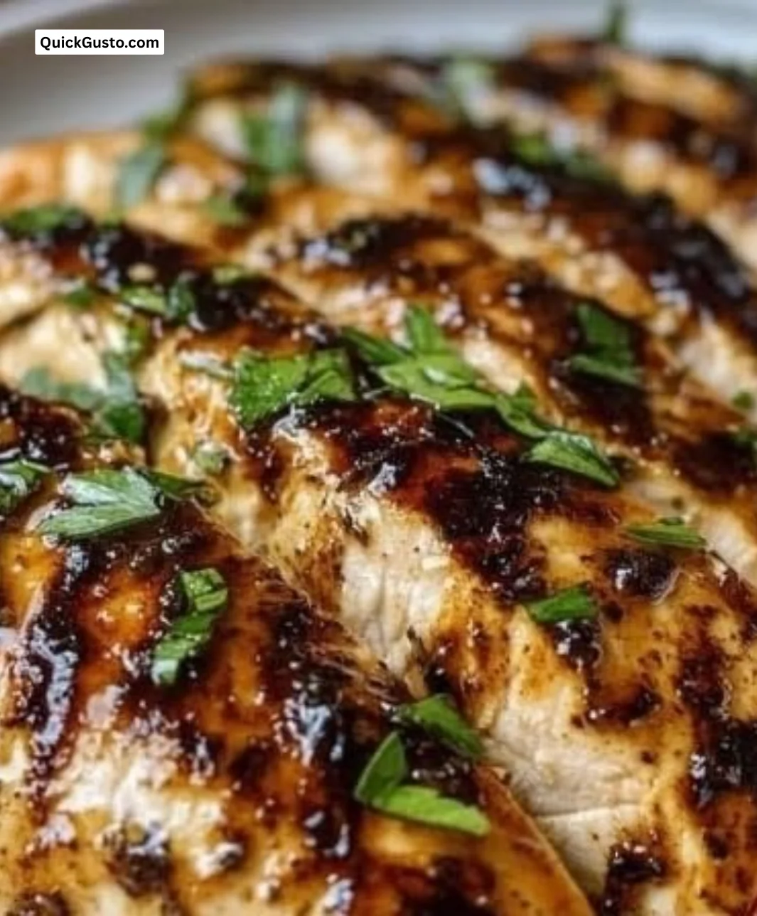 Juicy balsamic baked chicken breast served on a plate with herbs and sides.