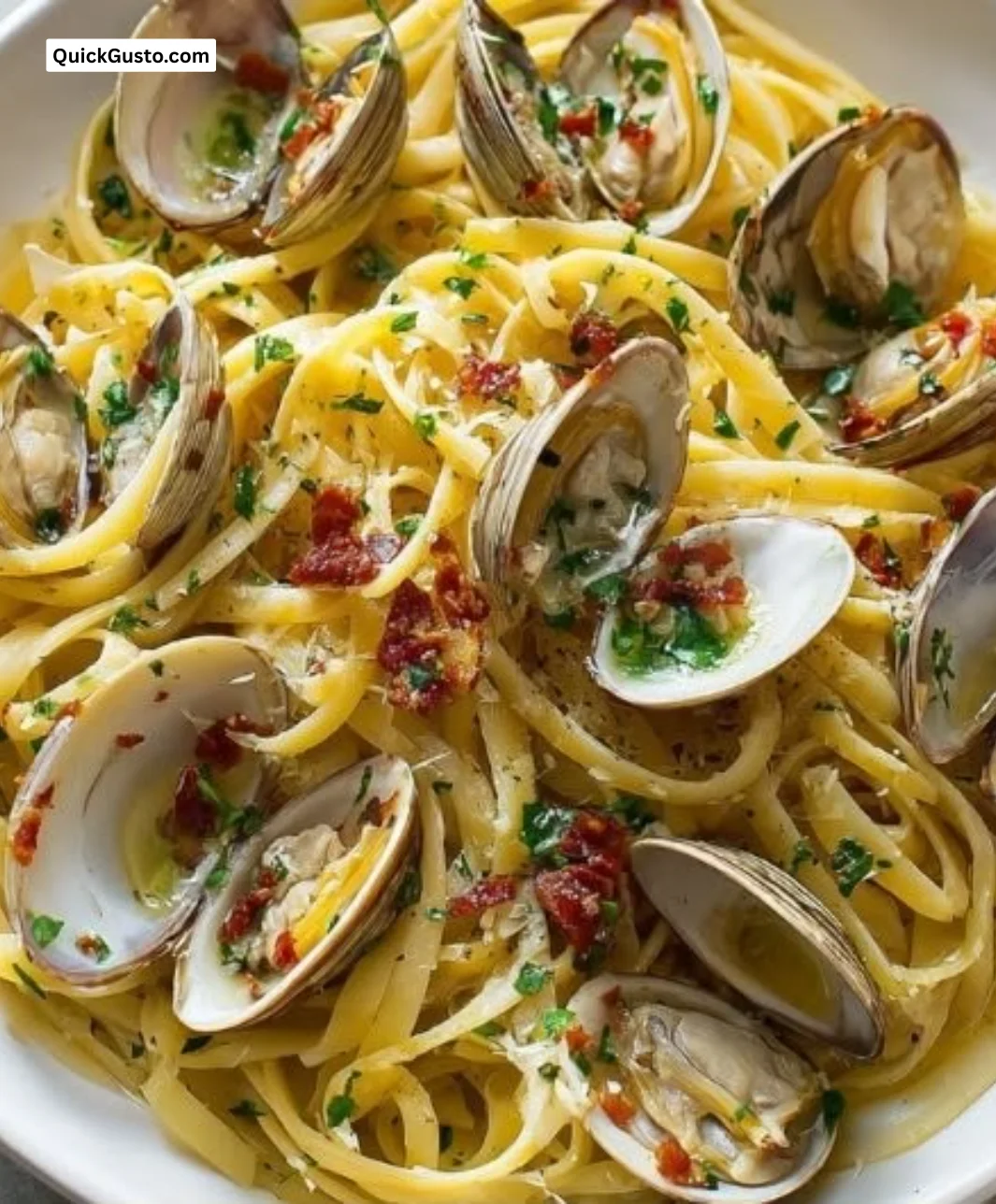 A delicious plate of linguine with clams garnished with parsley and lemon.