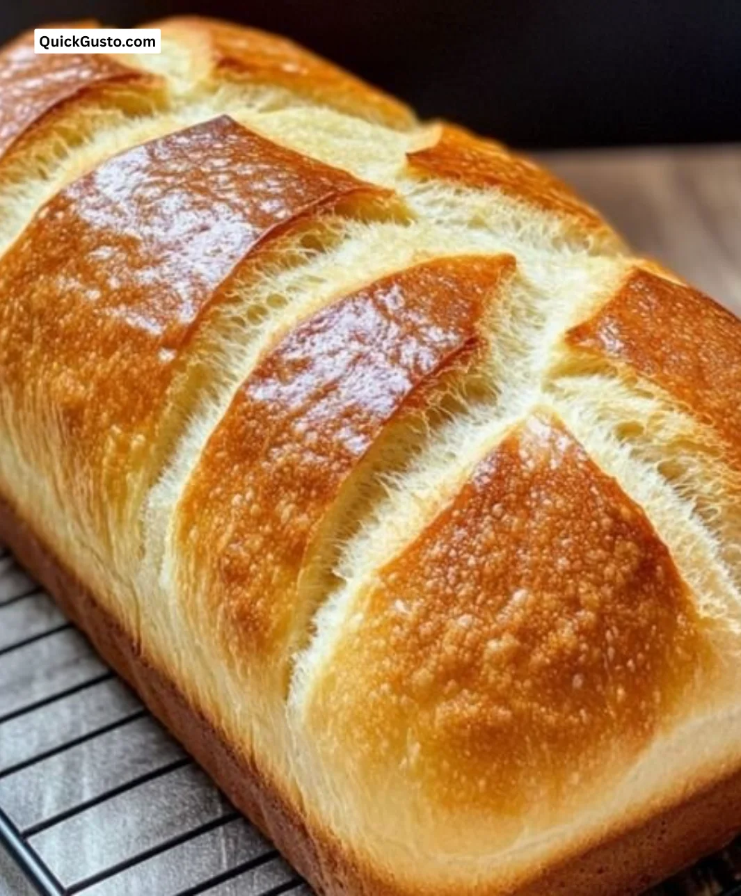 Loaf of soft sourdough sandwich bread on a wooden cutting board.