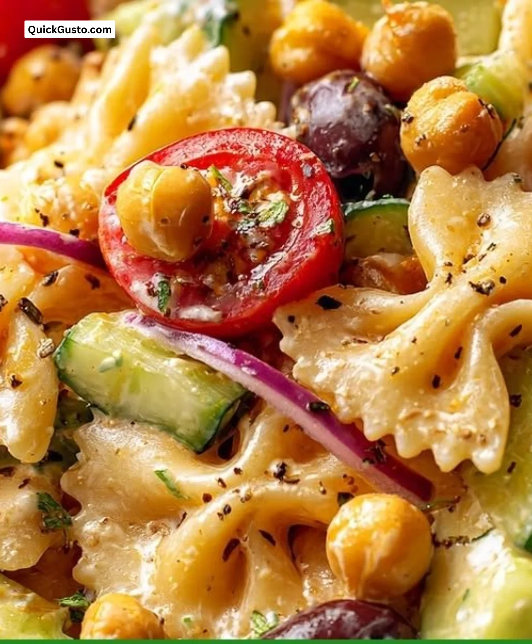 A colorful Vegan Greek Pasta Salad with chickpeas, tomatoes, and cucumbers in a bowl.