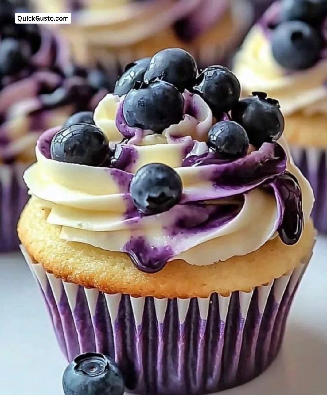 White chocolate blueberry cupcakes topped with creamy frosting and fresh berries