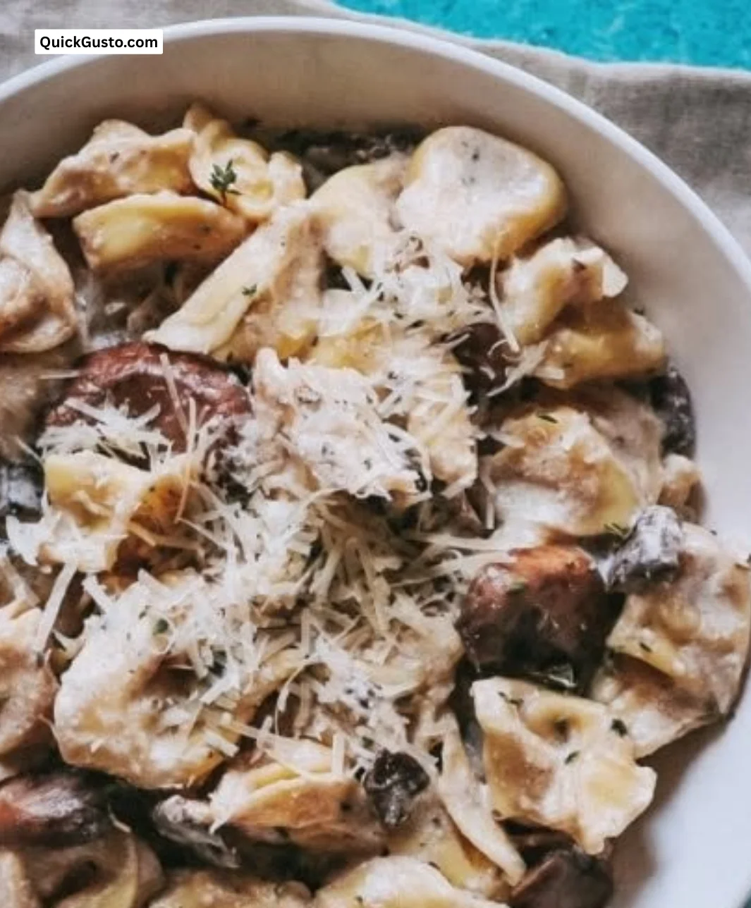 Plate of creamy Mushroom Tortellini Alfredo garnished with fresh herbs