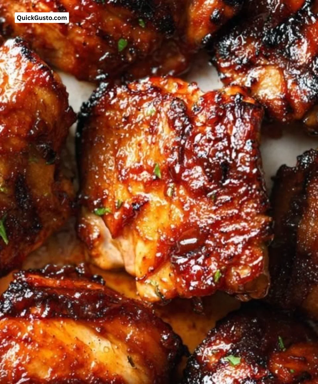 Caramelized BBQ chicken thighs baked in the oven, garnished and ready to serve