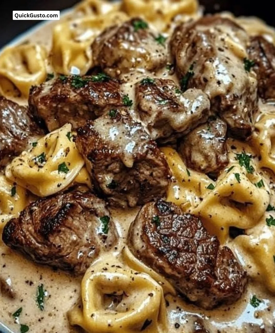Creamy garlic steak tortellini served in a white bowl with herbs
