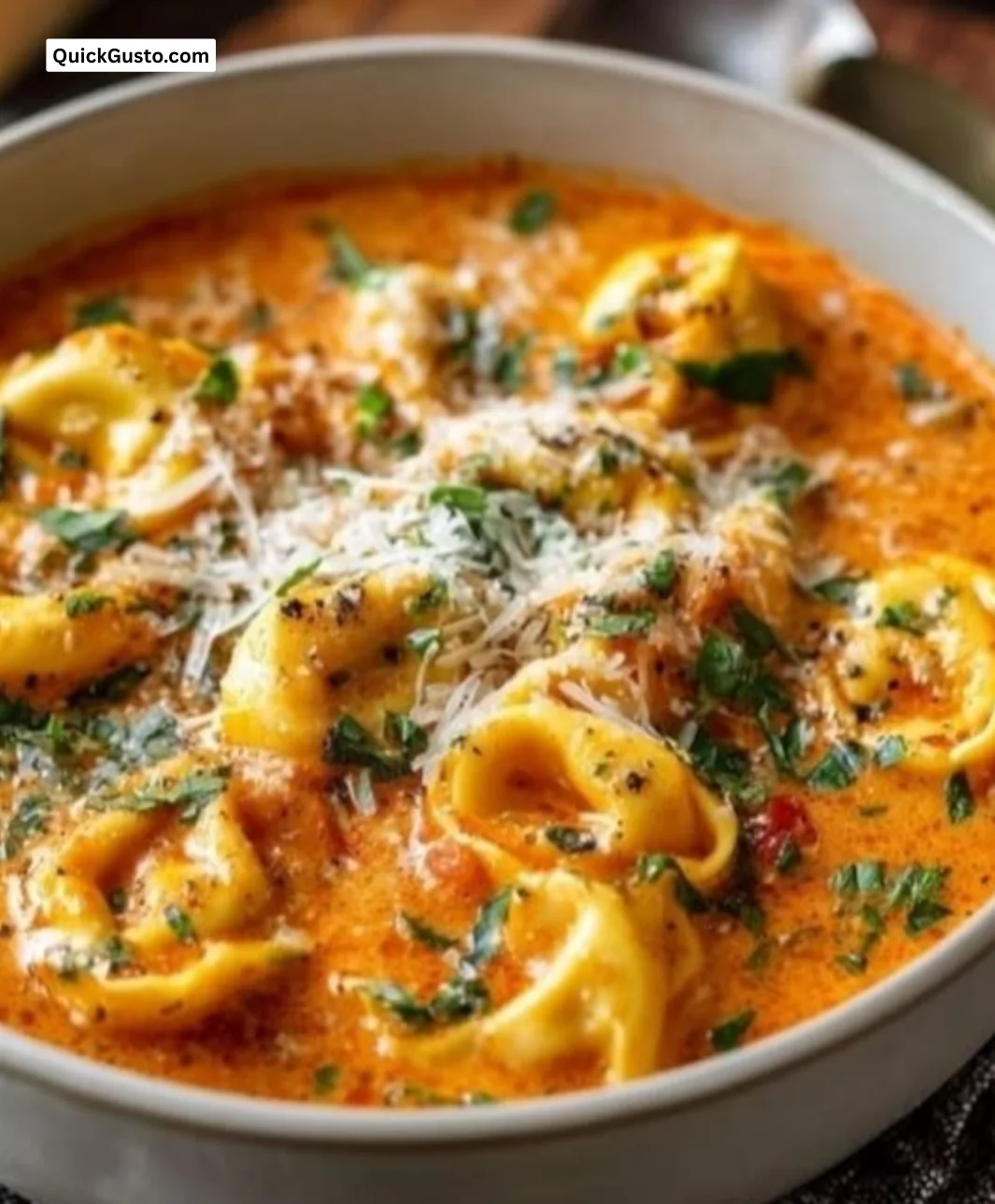 Bowl of creamy tomato tortellini soup garnished with fresh basil