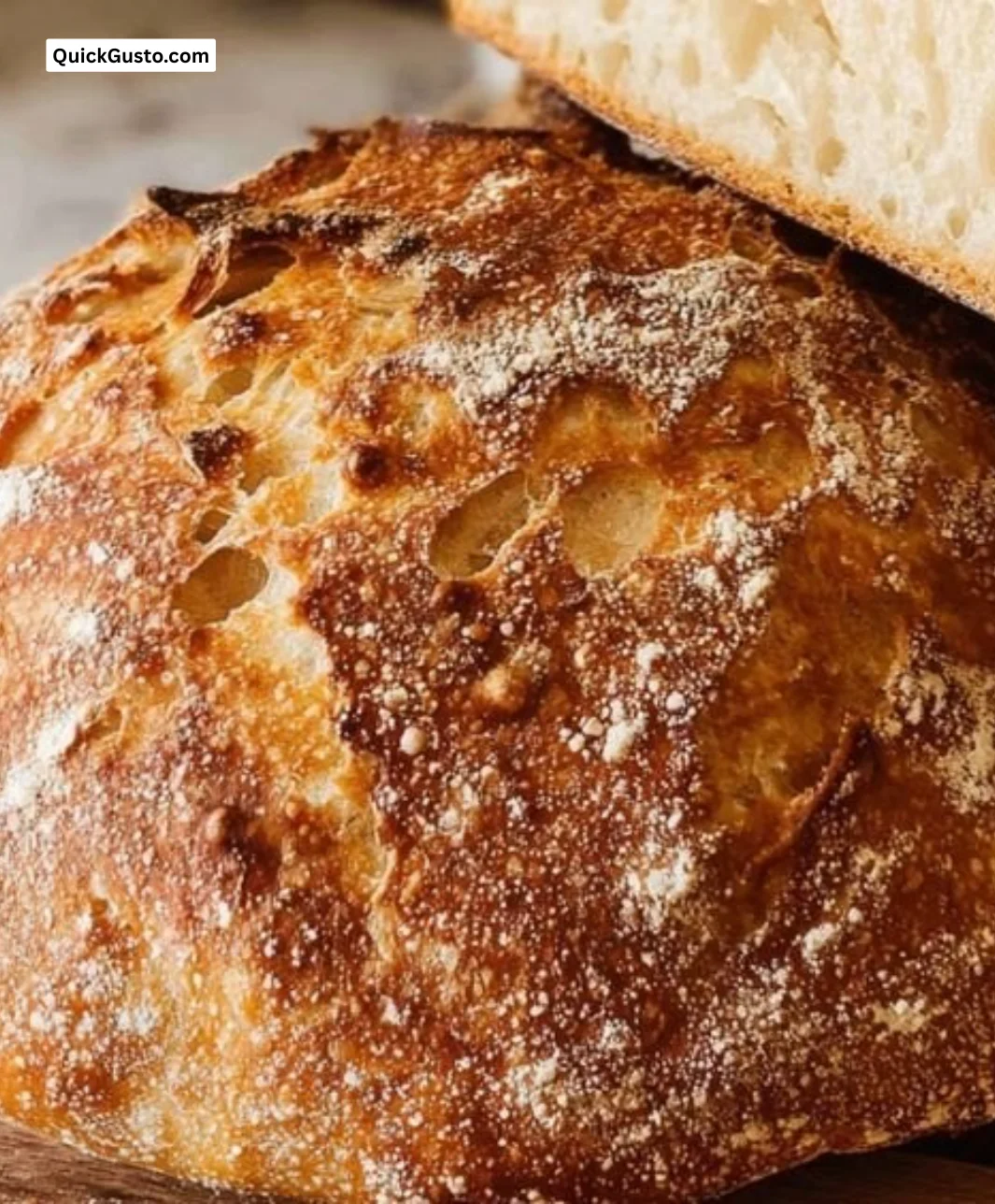 A beautifully baked sourdough bread sliced on a wooden board.