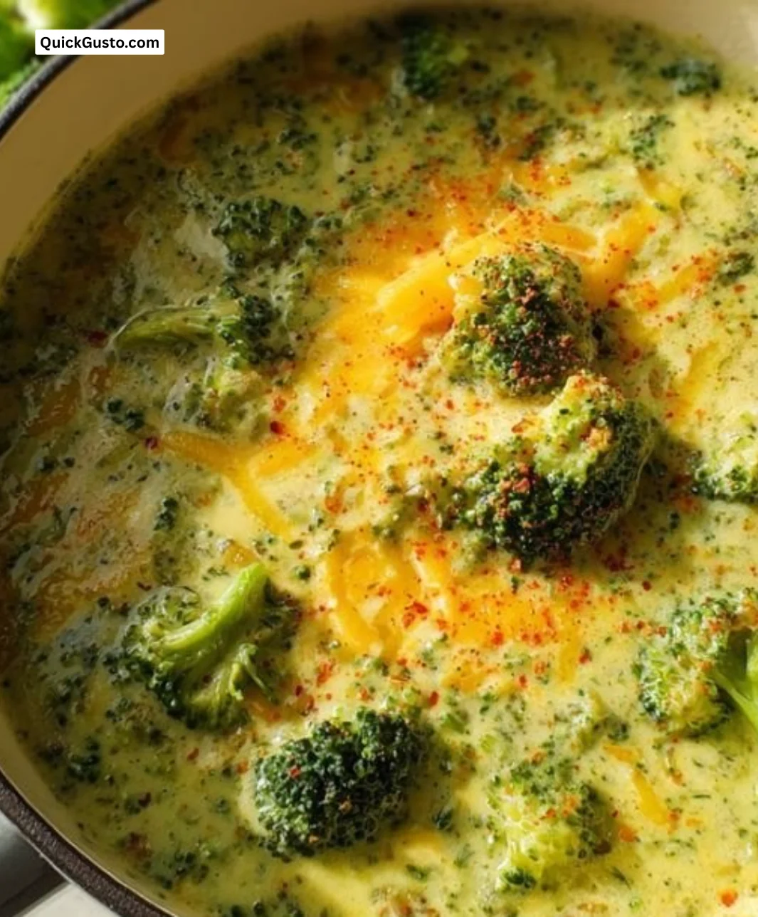 Bowl of high protein broccoli cheddar soup garnished with cheese and fresh broccoli