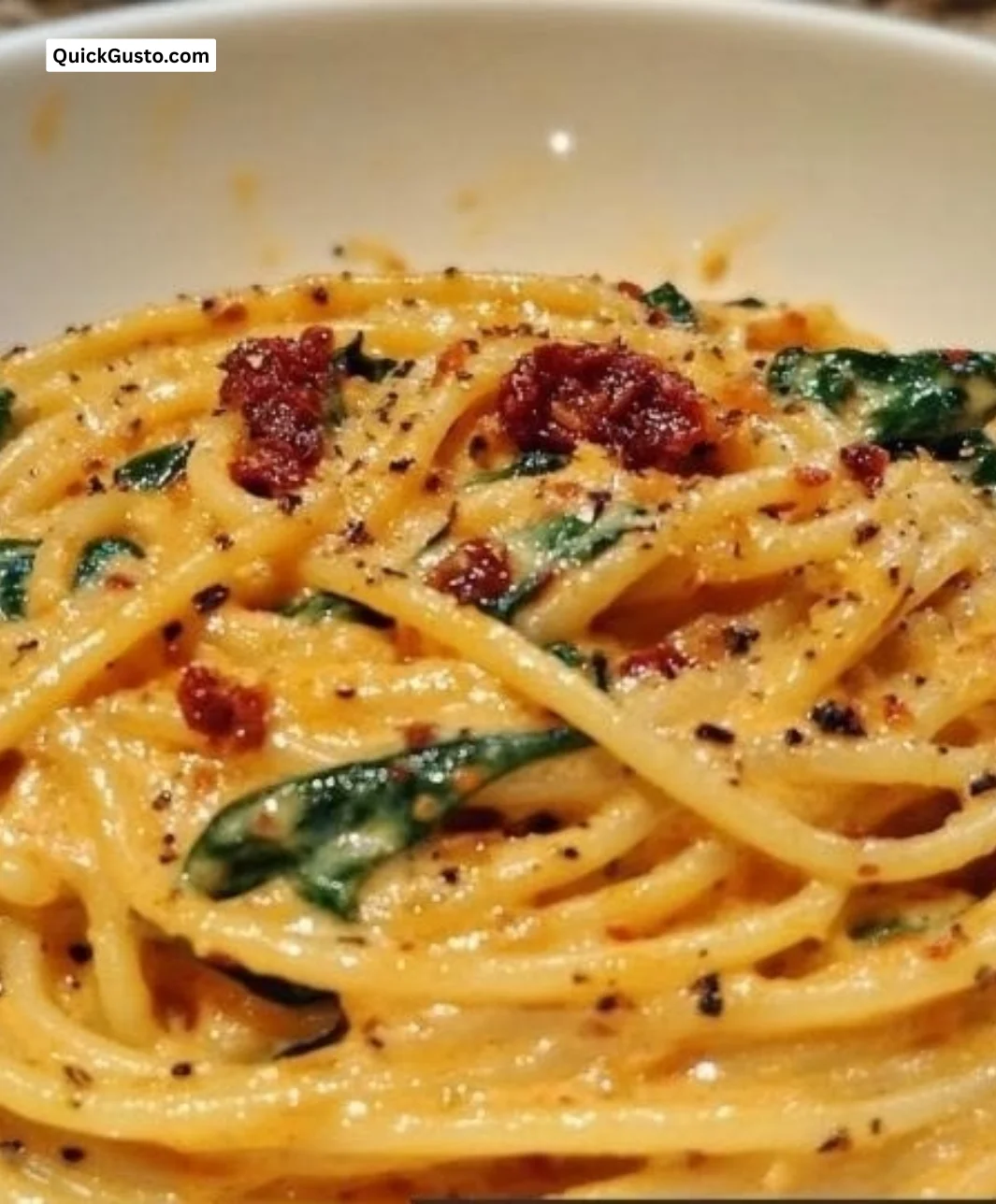 Plate of spaghetti with spinach in sun-dried tomato sauce garnished with herbs