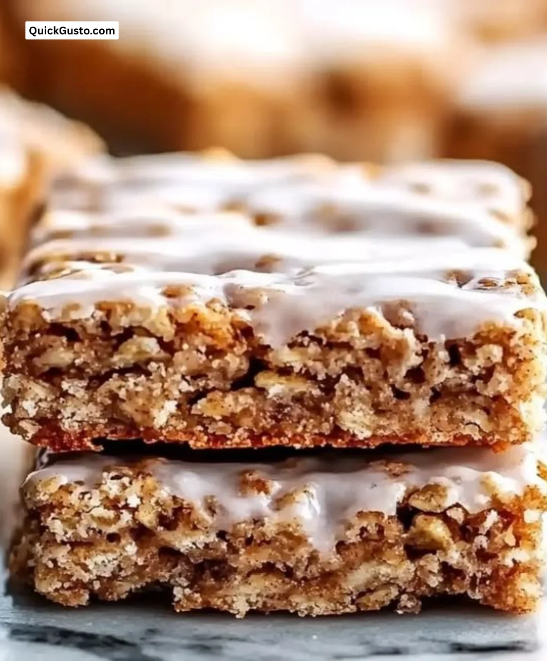 Cinnamon roll oatmeal bars topped with icing and cinnamon sprinkled on top.