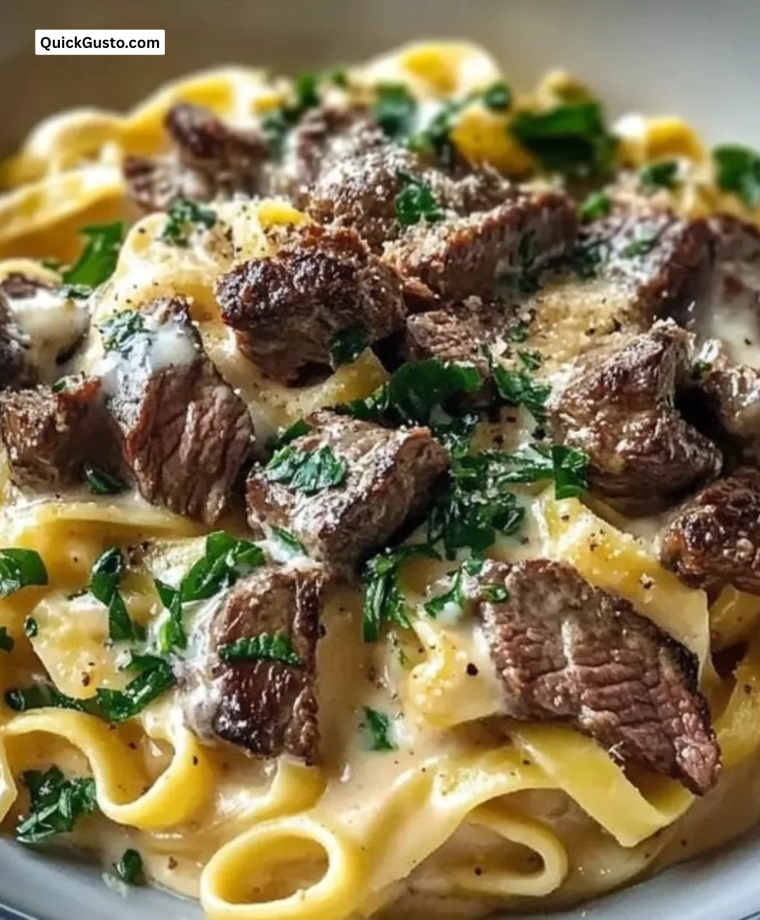 Creamy steak pasta dish garnished with herbs and served in a bowl