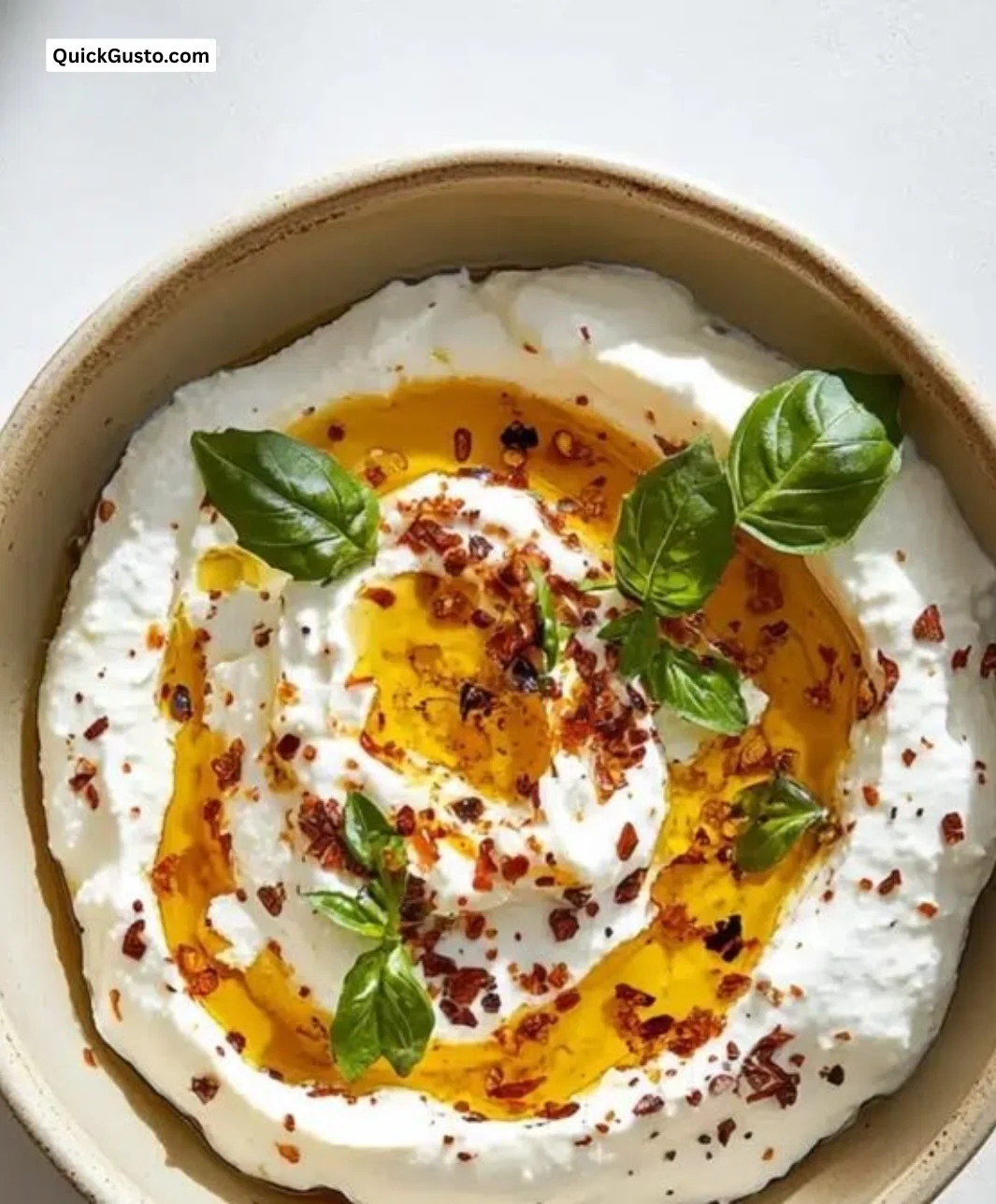 Creamy burrata dip served in a bowl with fresh herbs and toasted bread.
