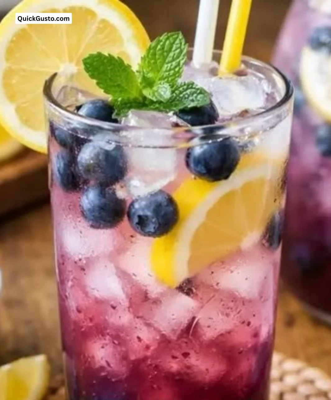 A tall glass of refreshing blueberry lemonade with fresh blueberries and lemon slices
