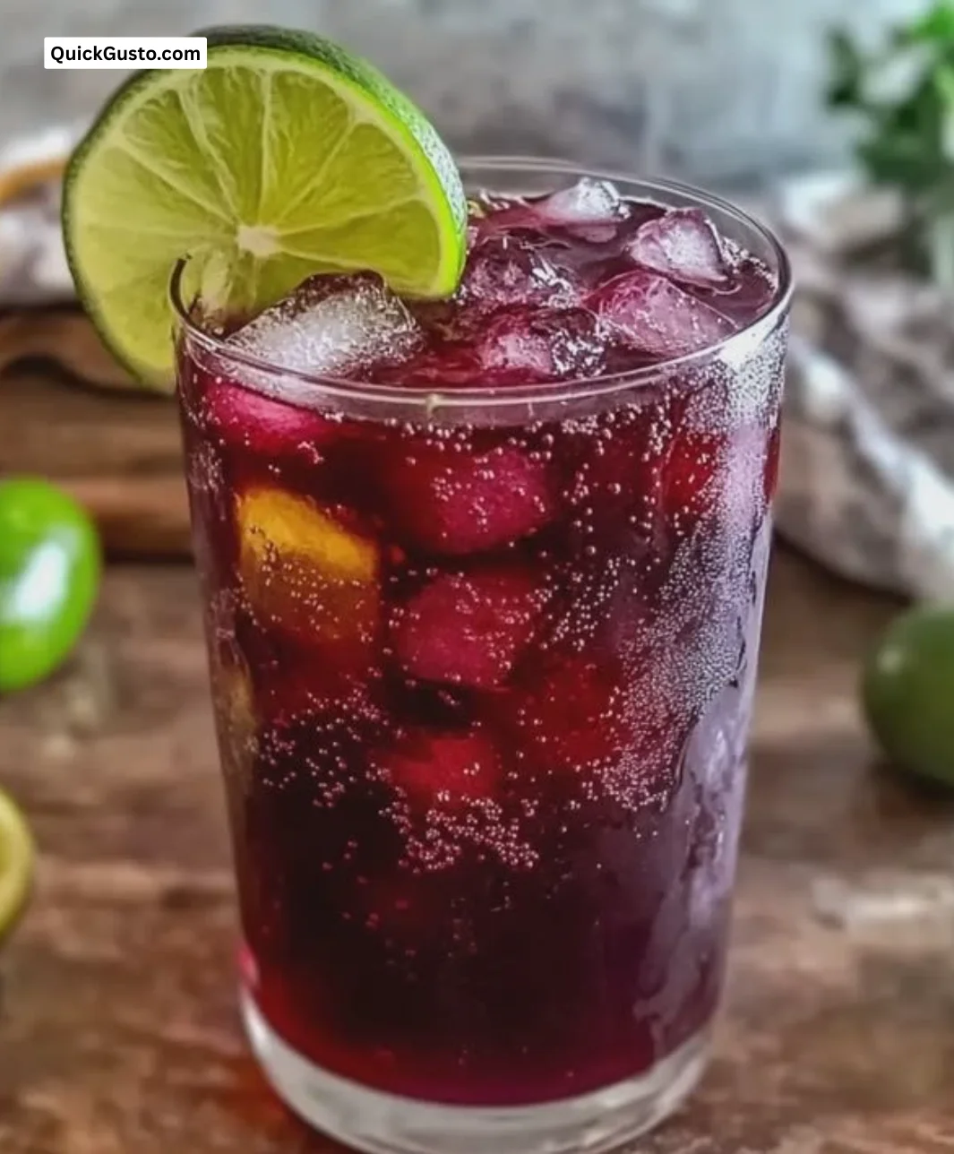 Glass of Hibiscus Ginger Iced Tea with Lime garnished with fresh mint