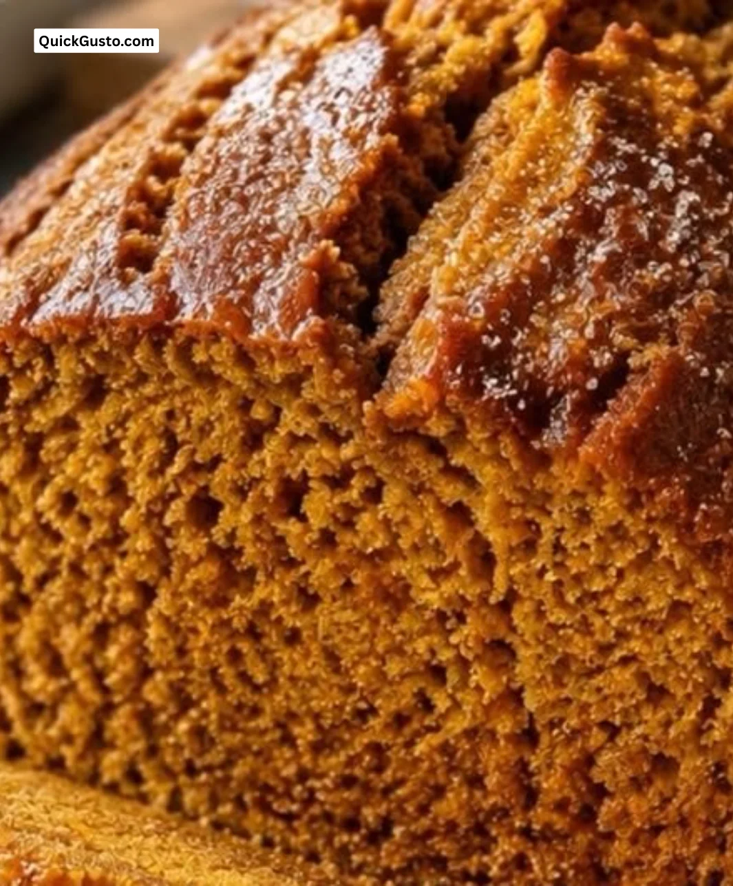 Slice of homemade pumpkin bread with spices and pumpkin seeds on a wooden table