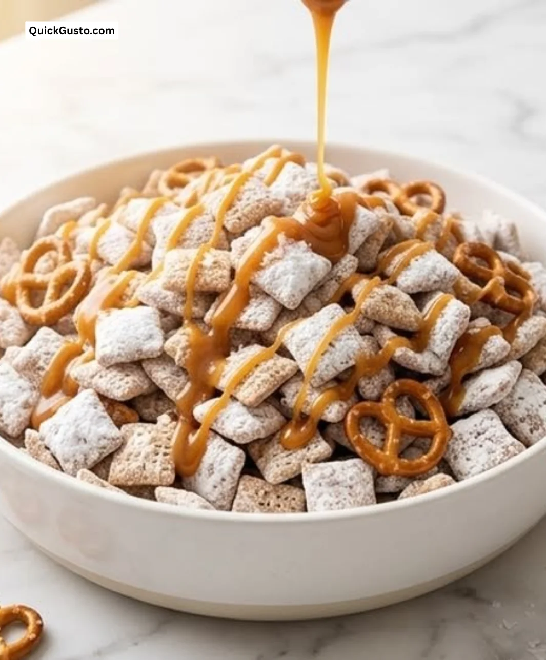 Bowl of Salted Caramel Pretzel Puppy Chow with pretzels and caramel drizzle