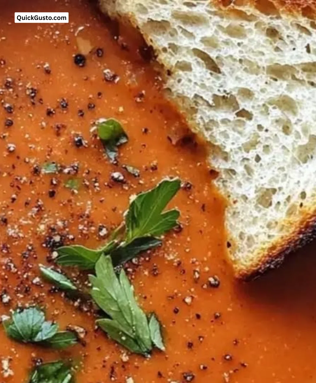 Bowl of spiced roasted red pepper tomato soup garnished with herbs